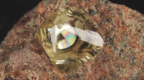 A yellow diamond entrapped in an orangey-brown rock